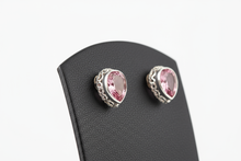 Load image into Gallery viewer, a pair of silver post back earrings with a PINK stone on a black faux leather jewelry display with a white background