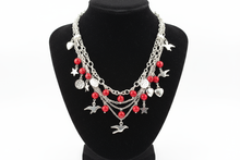 Load image into Gallery viewer, a necklace of silver chains with red colored and charms on a black bust with a white background

