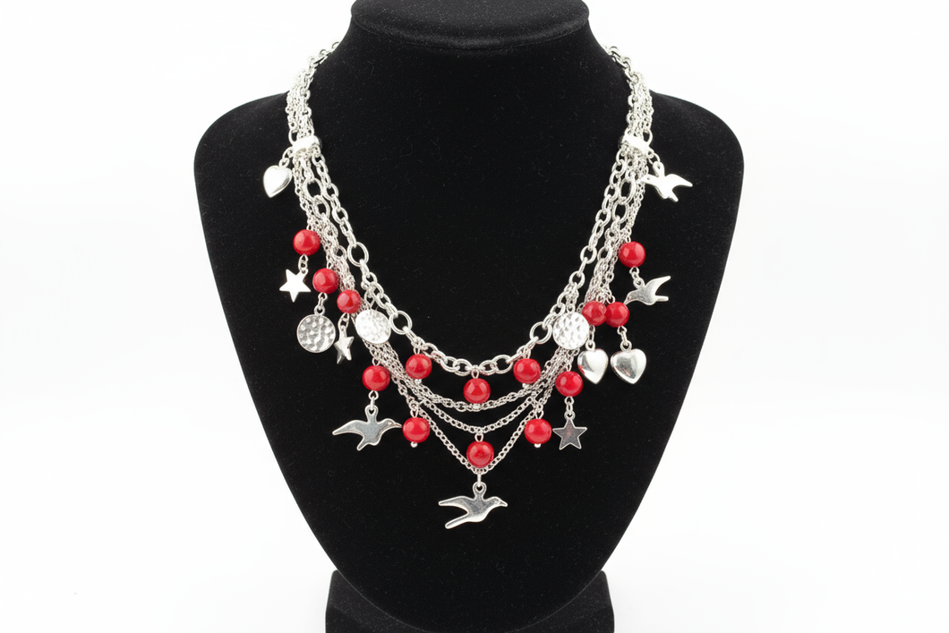 a necklace of silver chains with red colored and charms on a black bust with a white background