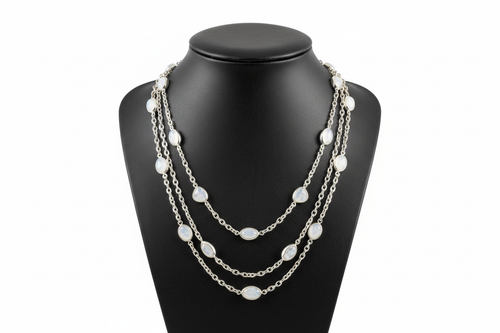 a necklace of silver chains with WHITE colored STONES on a black faux leather jewelry display bust with a white background