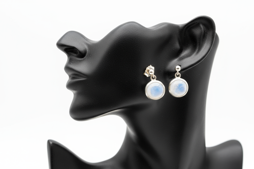 a pair of silver post back earrings with a white stone on a black faux leather jewelry display with a white background