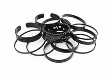 Load image into Gallery viewer, black metal bracelets, consisting of elastic, cuff and bangle styles, clustered together with a white background
