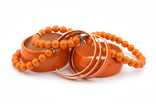 Load image into Gallery viewer, Orange bracelets, consisting of elastic, cuff and bangle styles, clustered together with a white background
